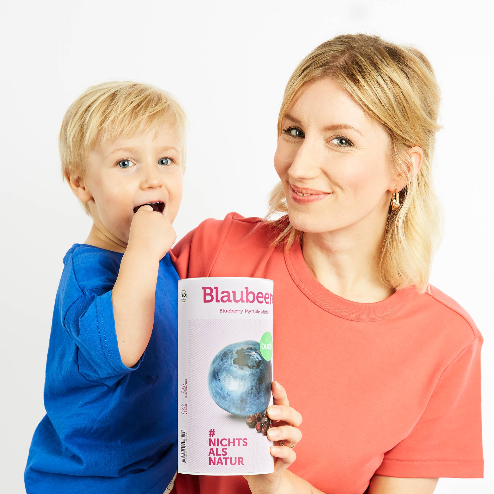 Mama mit Sohn auf dem Arm und einer Dose buah Blaubeeren in der Hand