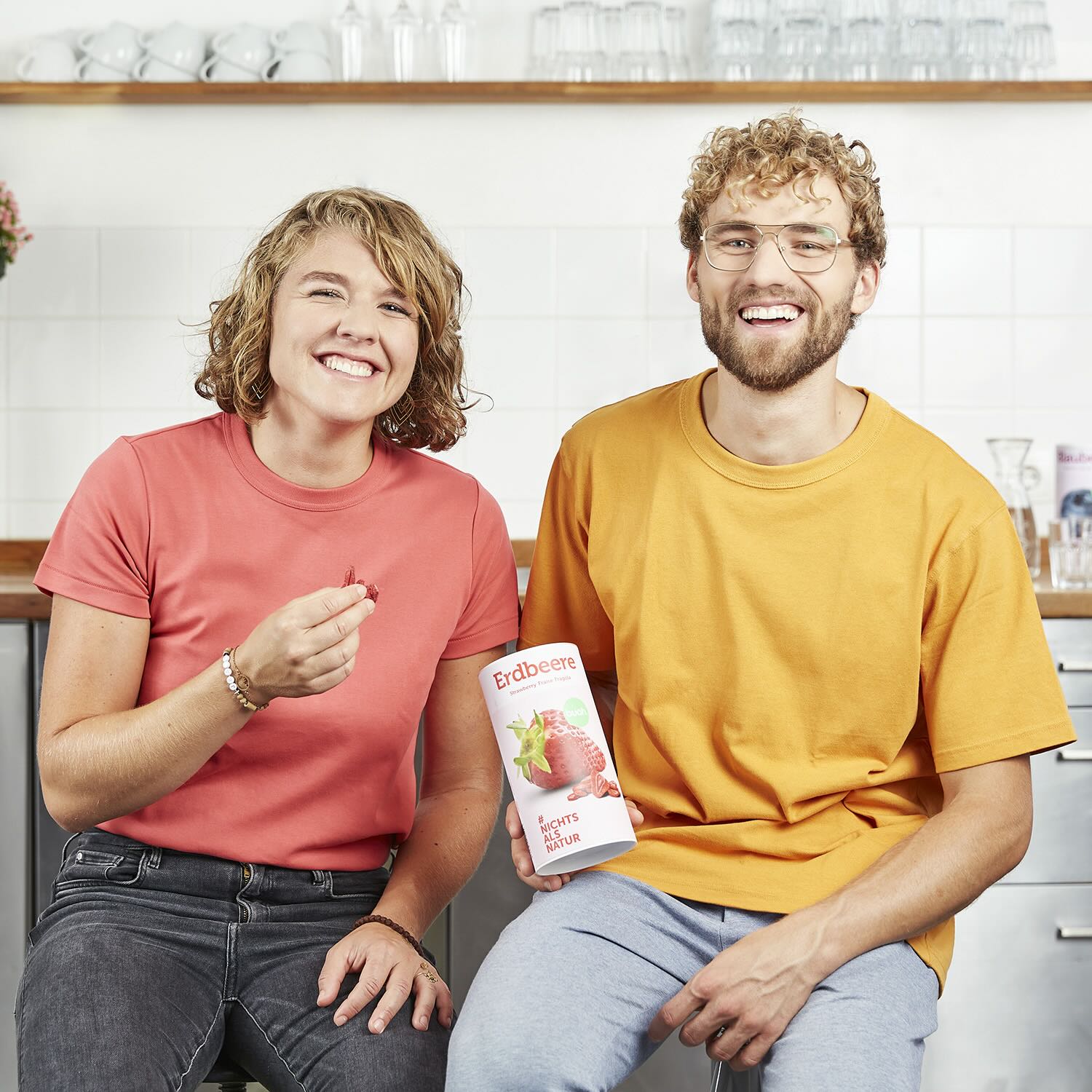 buah Gruender Jessica und Daniel Krauter lachen in Kamera mit Dose buah Erdbeeren