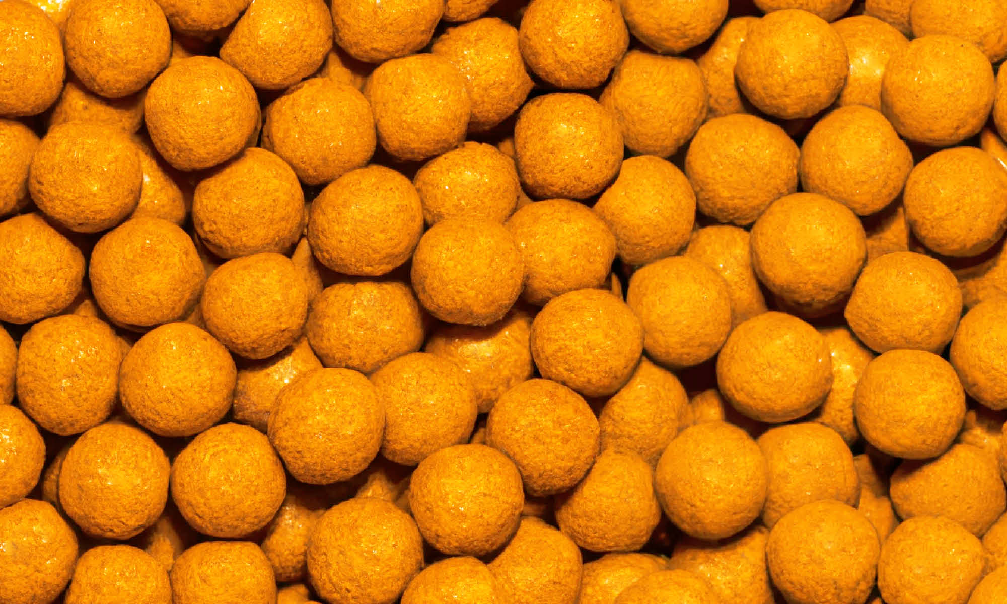 Viele kleine, runde, gelbe Ananas-Maracuja Kaubonbon von buah neben und aufeinander