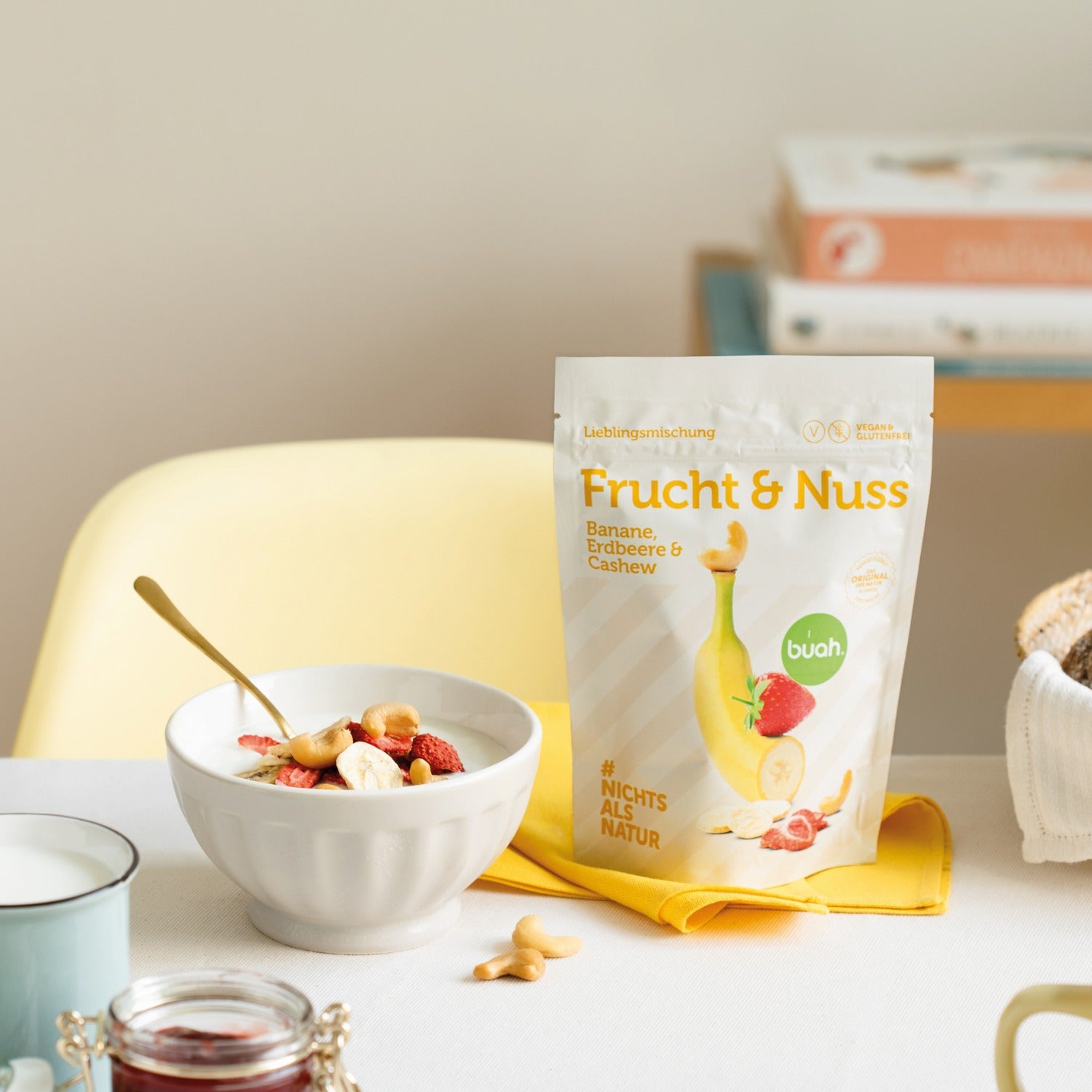 Packung buah Frucht & Nuss Banane, Erdbeere und Cashew neben einer Schale mit Joghurt garniert mit buah Frucht & Nuss Mischung