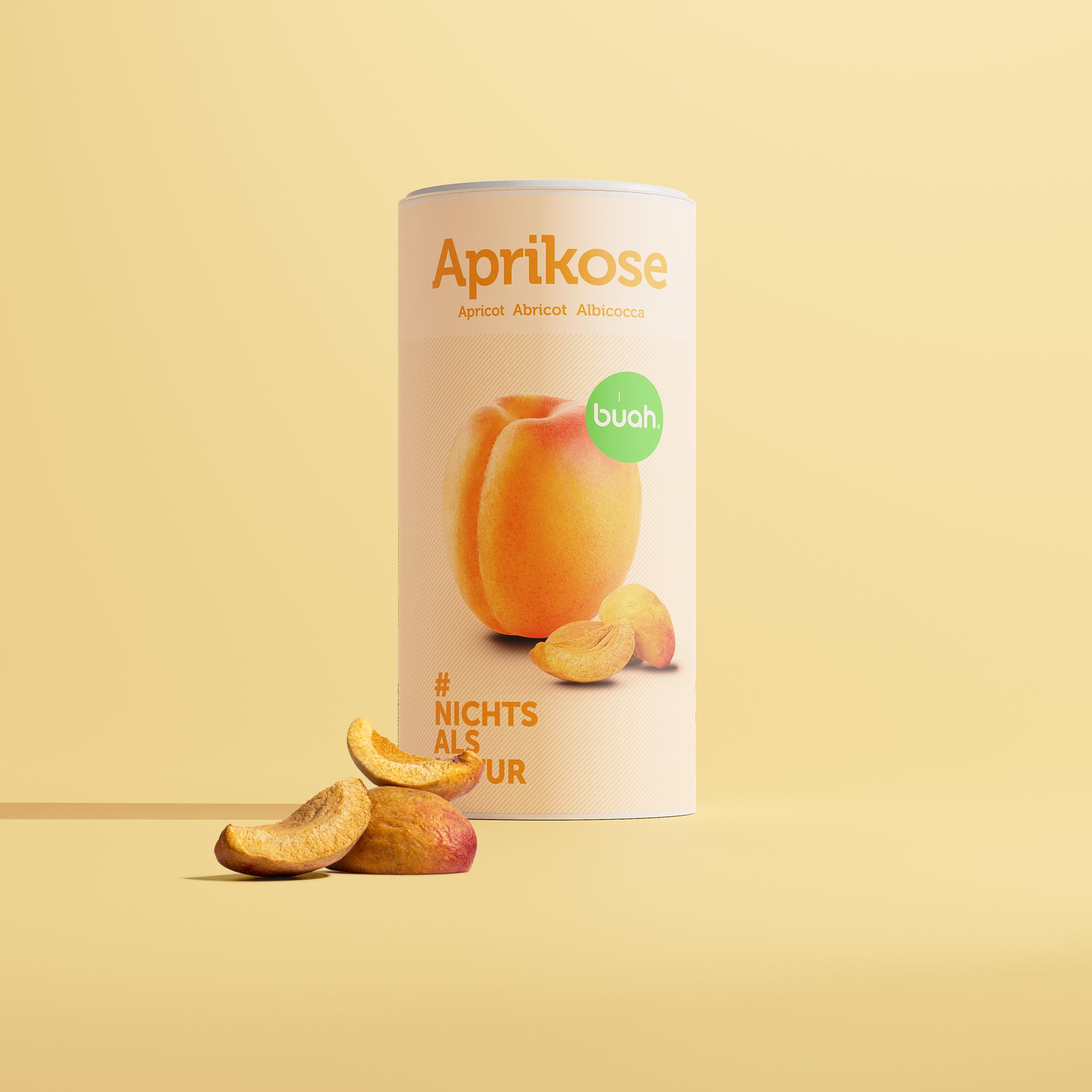 buah gefriergetrocknete Aprikose in der grosser Dose mit Aprikosen Schnitzen vor der Dose und gelbem Hintergrund