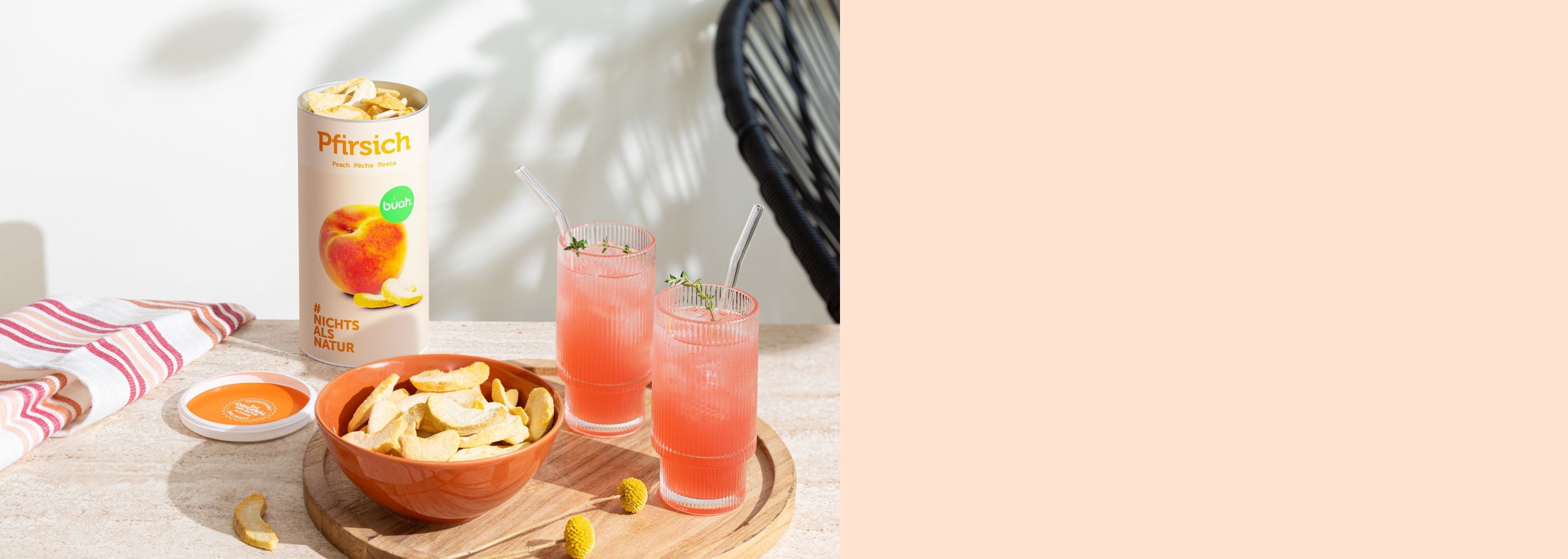 Schale mir buah gefriergetrocknetem Pfirsich auf Holztablett, daneben zwei Pfirsich Mocktail, im Hintergrund buah gefriergetrockneter Pfirsich in grosser Dose