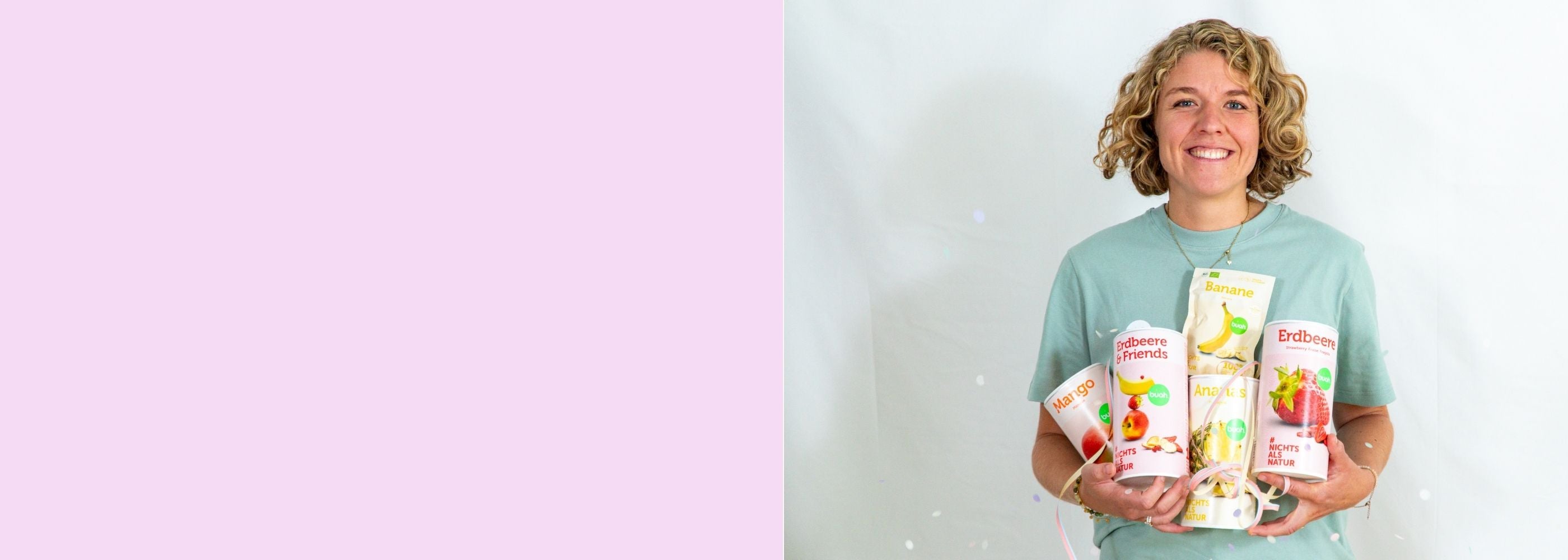 Jessica Gruenderin von buah in gruenem buah Shirt mit buah gefriergetrockneten Fruechten in der Dose im Arm - Konfetti und Luftschlangen vor rosa Hintergrund  