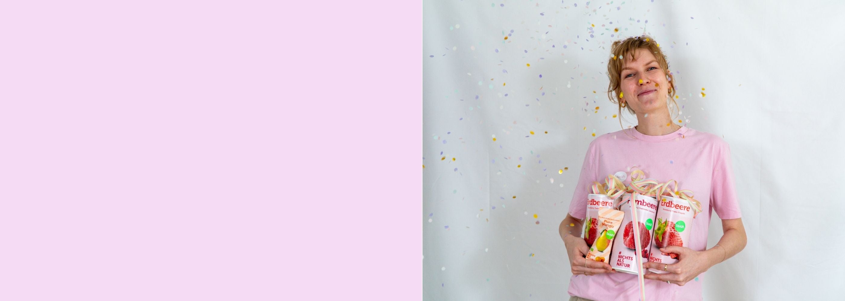 Sarah von buah im rosa buah Shirt mit buah gefriergetrockneten Fruechten in der Dose im Arm - Konfetti und Luftschlangen vor rosa Hintergrund