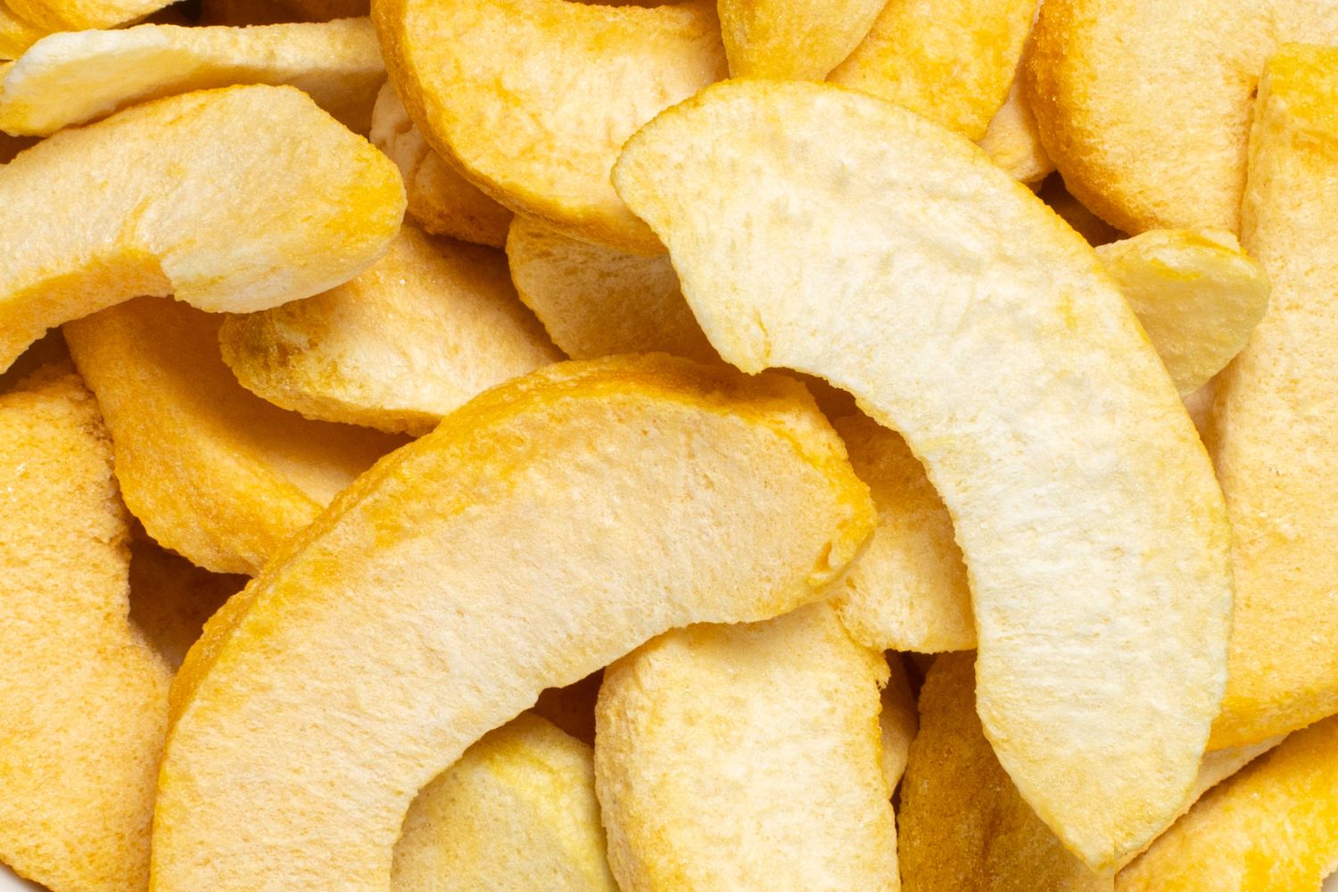 Viele buah gefriergetrockneter Pfirsich Schnitze in hellgelb und dunklerem gelb liegen auf und nebeneinander