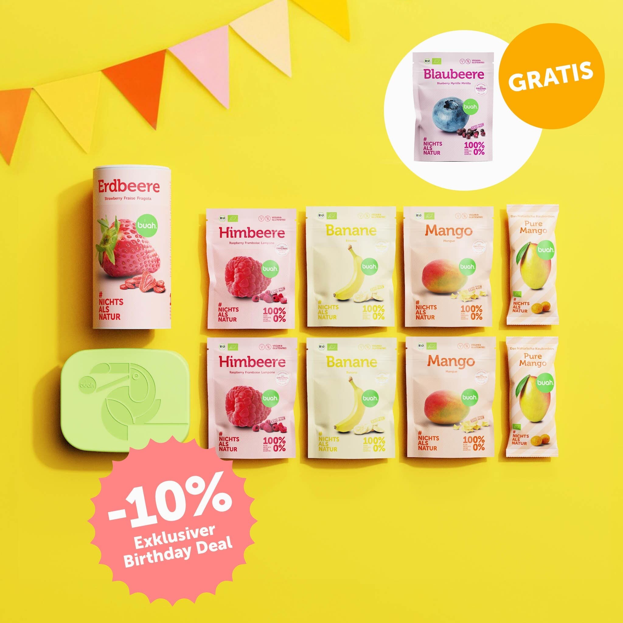 buah Birthday Set mit buah gefriergetrockneter Erdbeere, Lunchbox und diveresen Snakcpacks vor gelbem Hintergrund mit bunten Girlanden im Hintergrund, 10% Badge im Bild und Blaubeere Snackpack kostenlos