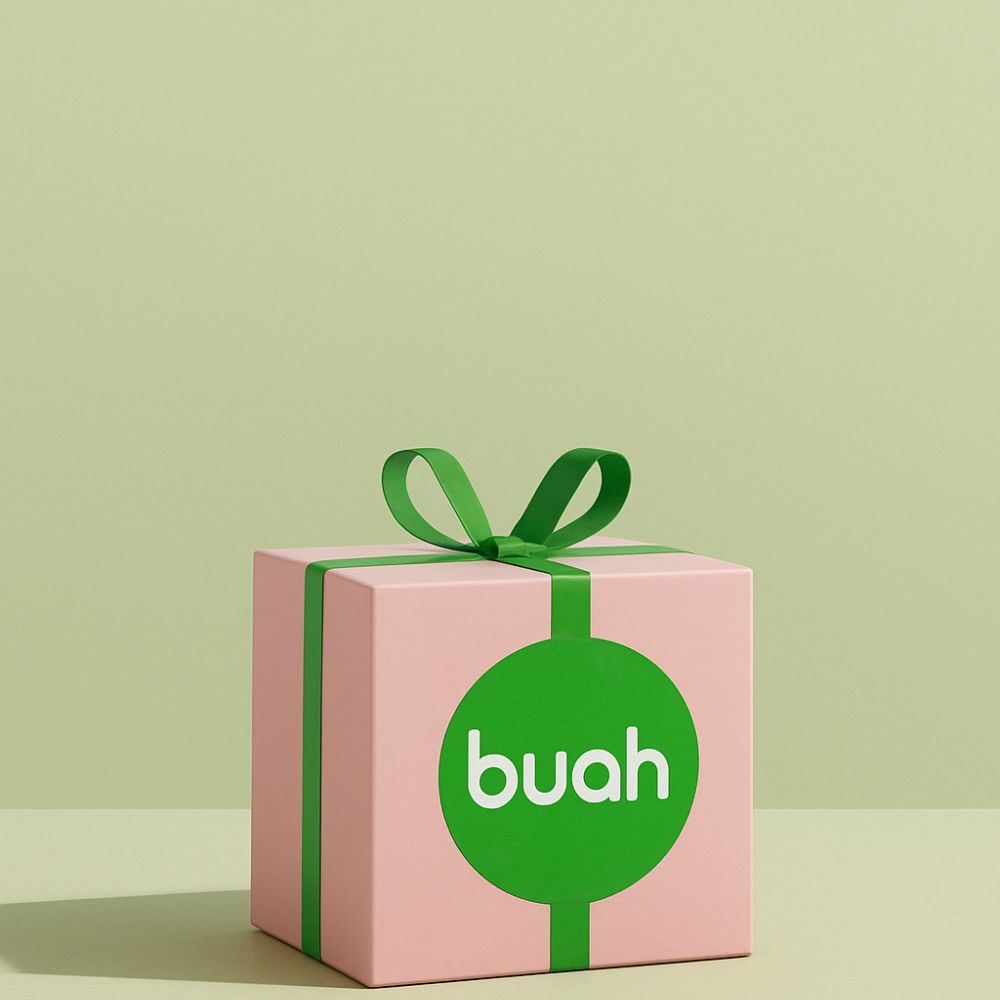 Weihnachtsgeschenk in Rosa mit gruener Schleife und Geschenkband, buah Logo auf Geschenk vor Pastell gruenem Hintergrund, Geschenkideen