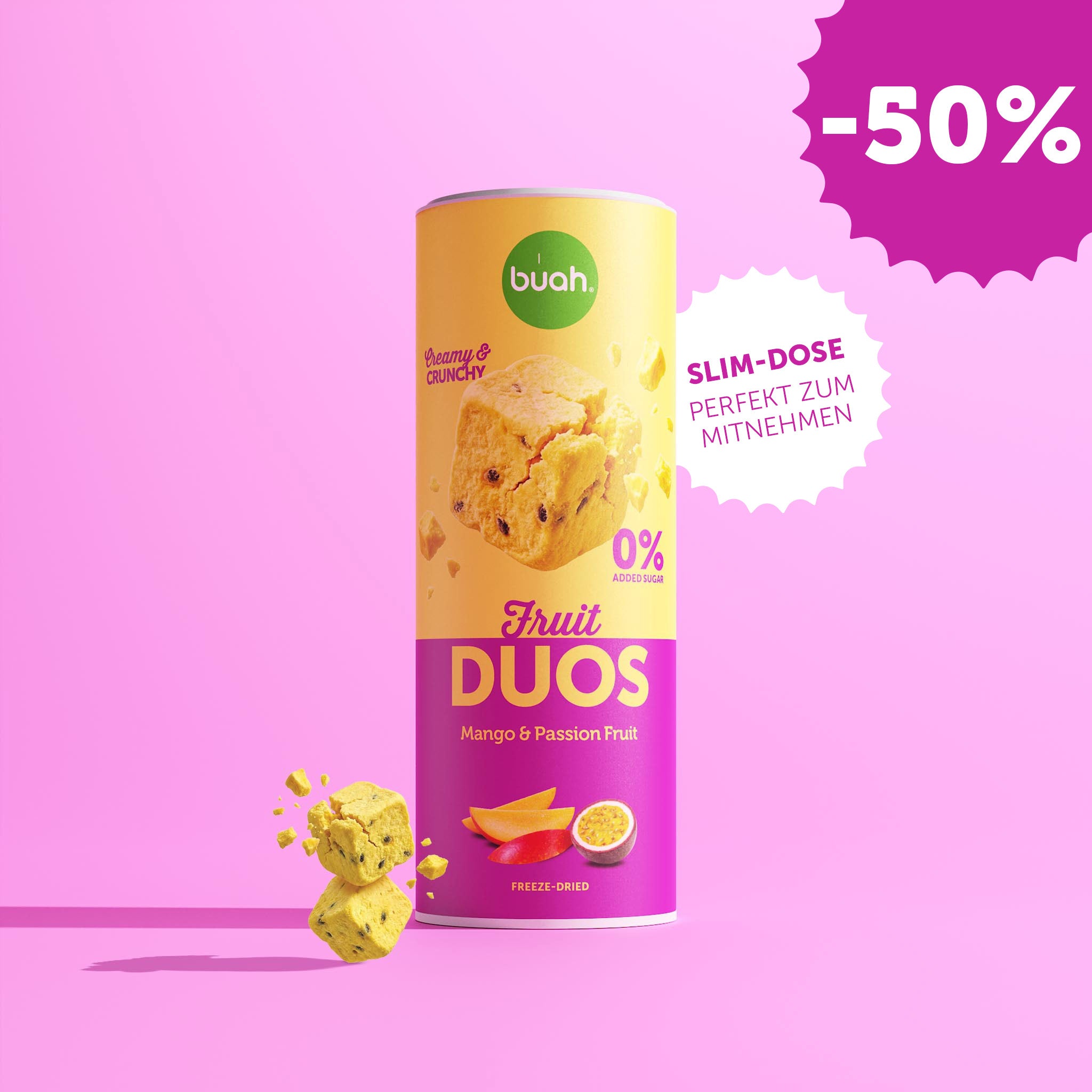 Eine Slim-Dose buah Fruit DUOS Mango & Maracuja steht im Zentrum vor einem rosafarbenen Hintergrund. Daneben steht in einer weißen, gezackten Blase: „SLIM-DOSE PERFEKT ZUM MITNEHMEN“. Links schweben Fruchtwürfel.