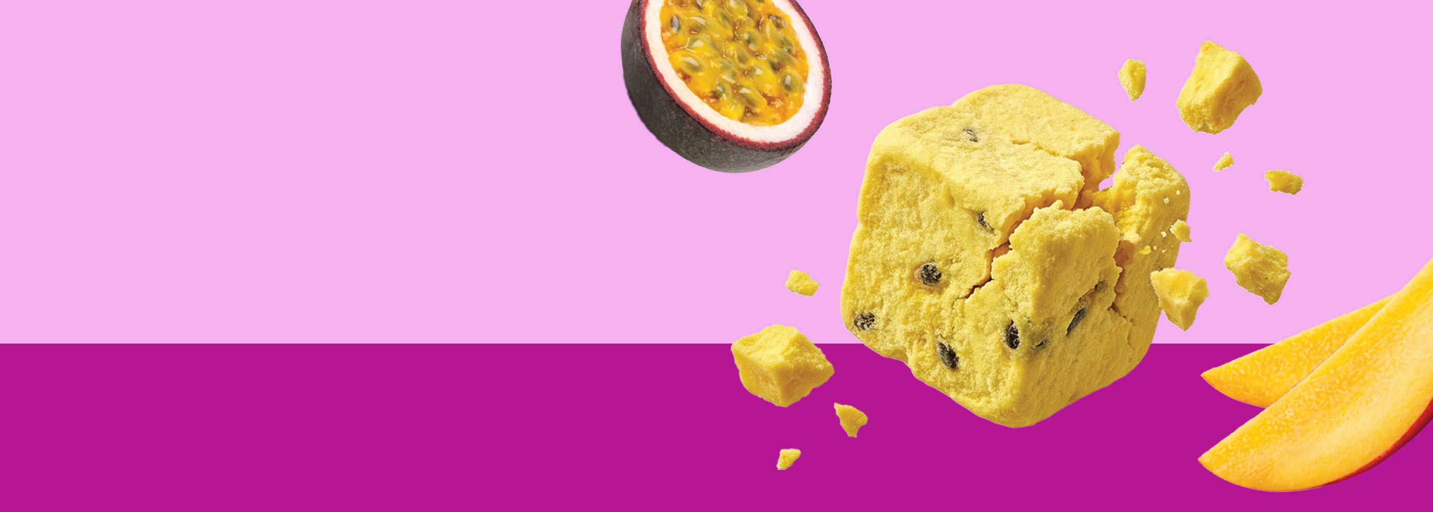 Ein breites Banner. Ein zerbrechender buah gefriergetrockneter Fruchtwürfel (Mango & Maracuja) schwebt im Zentrum. Links fliegt eine angeschnittene Maracuja-Hälfte, rechts fliegen Mangoschnitze. Der Hintergrund ist horizontal geteilt: oben hellrosa, unten dunkelpink.